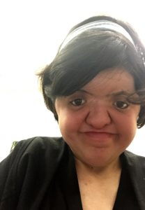 Photo of a young woman dressed in black with a white hair band.