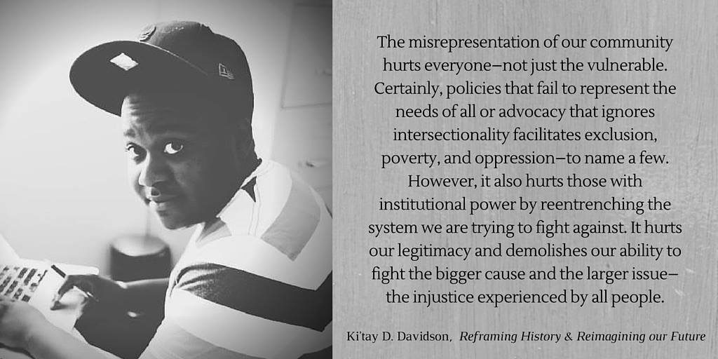 Black/white photo of a black youth wearing a dark baseball cap and striped shirt. He is holding a pen looking at the camera over his shoulder as he types on his laptop.